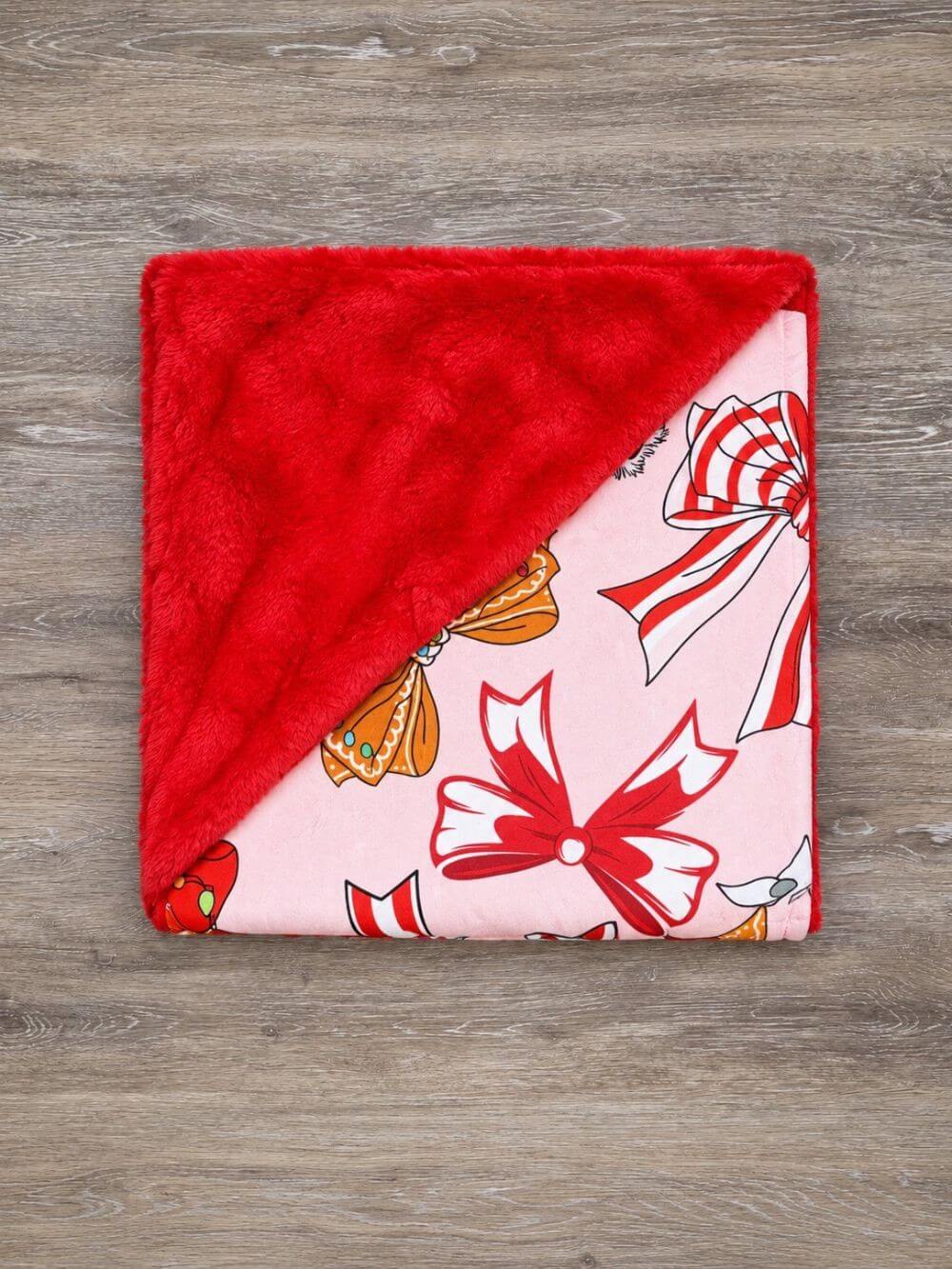 Christmas coquette bow baby blanket with red fleece backing folded to show the patterned front and reverse