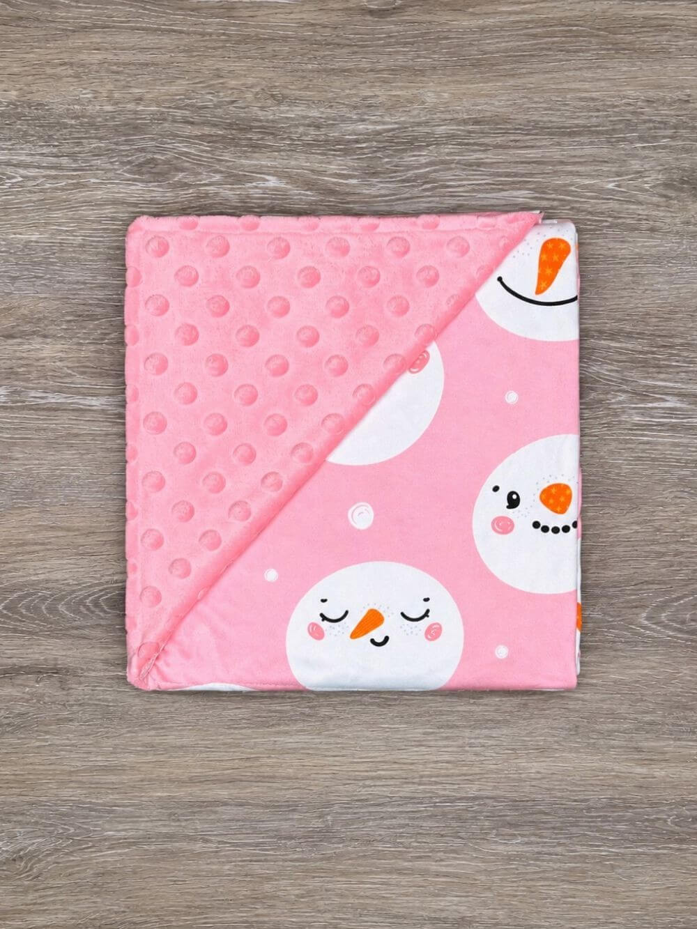 Pink snowman baby blanket with pink minky dot backing folded to show the patterned front and reverse